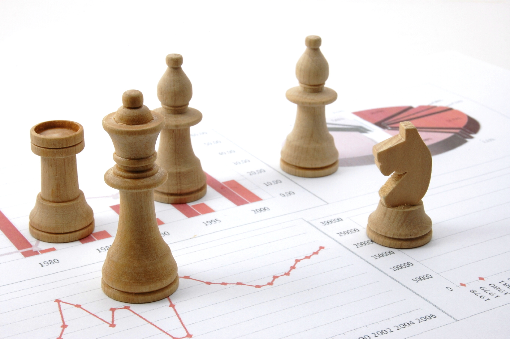 Holz-Schachfiguren auf Finanzdiagrammen als Symbol für strategische Planung